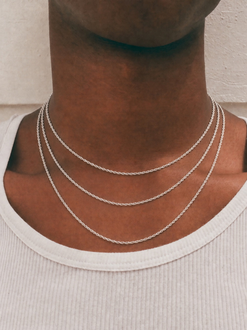 Front view of a model wearing four stacked sterling silver rope chains at 18, 20, 22, and 24 inches